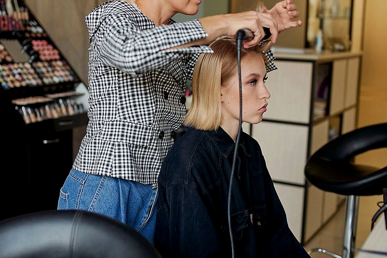 Free Side view of focused hairdresser straightening hair of confident female client with iron in hairdressing salon Stock Photo