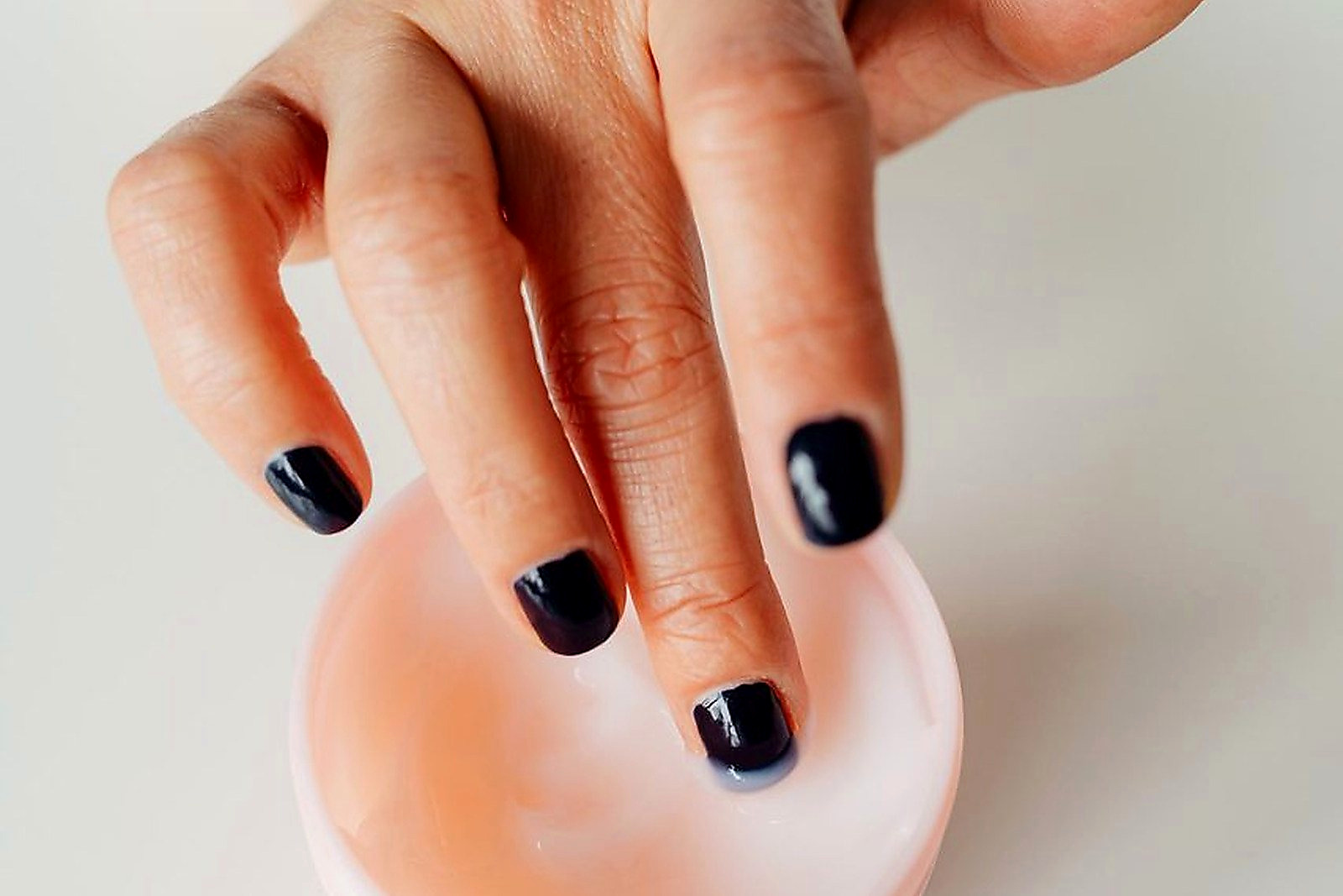 Free A close-up shot of a woman's hand with black-painted nails applying a moisturizing cream. Stock Photo