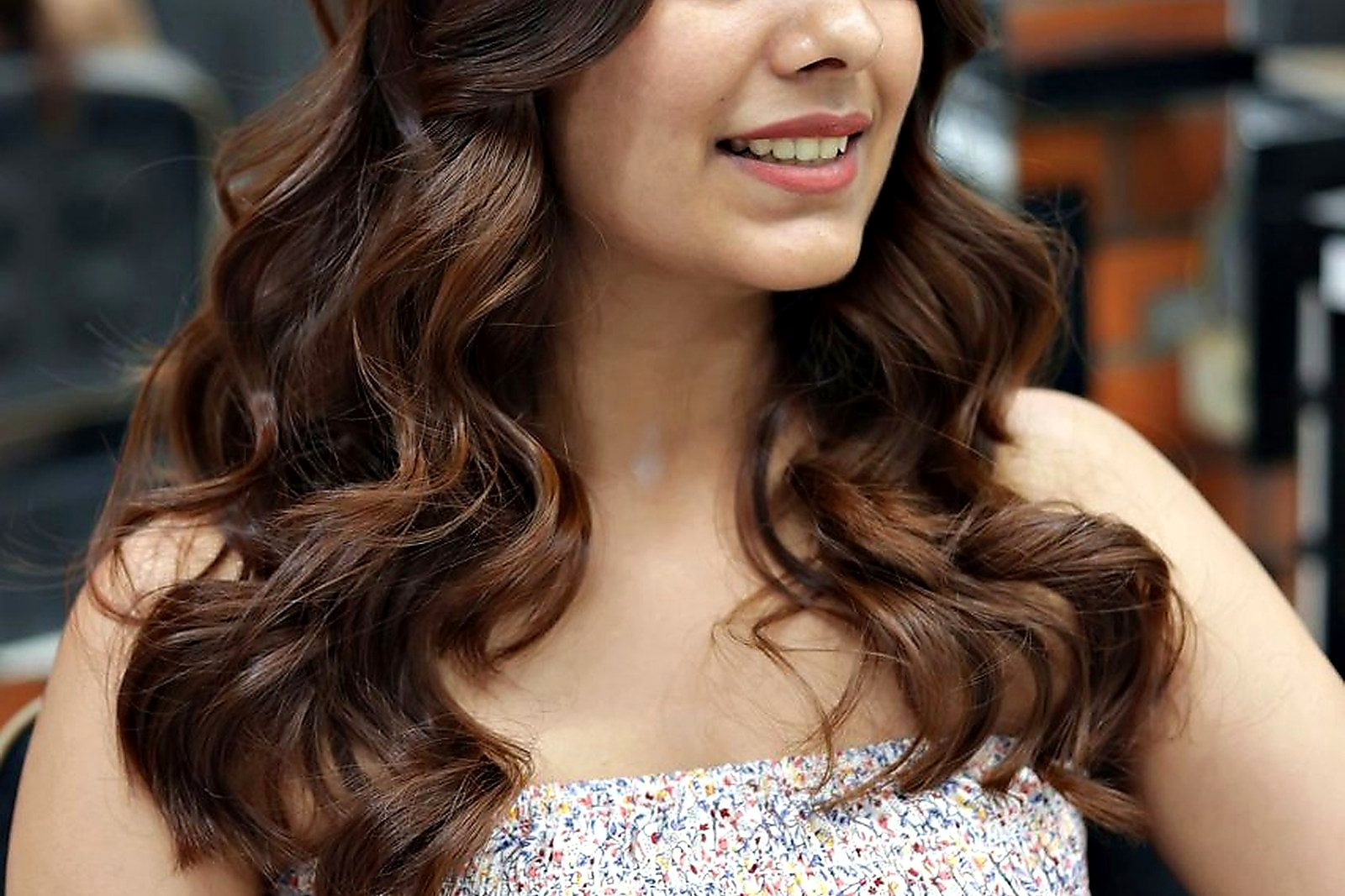 Free Portrait of a woman with wavy brunette hair, smiling in a salon setting. Stock Photo